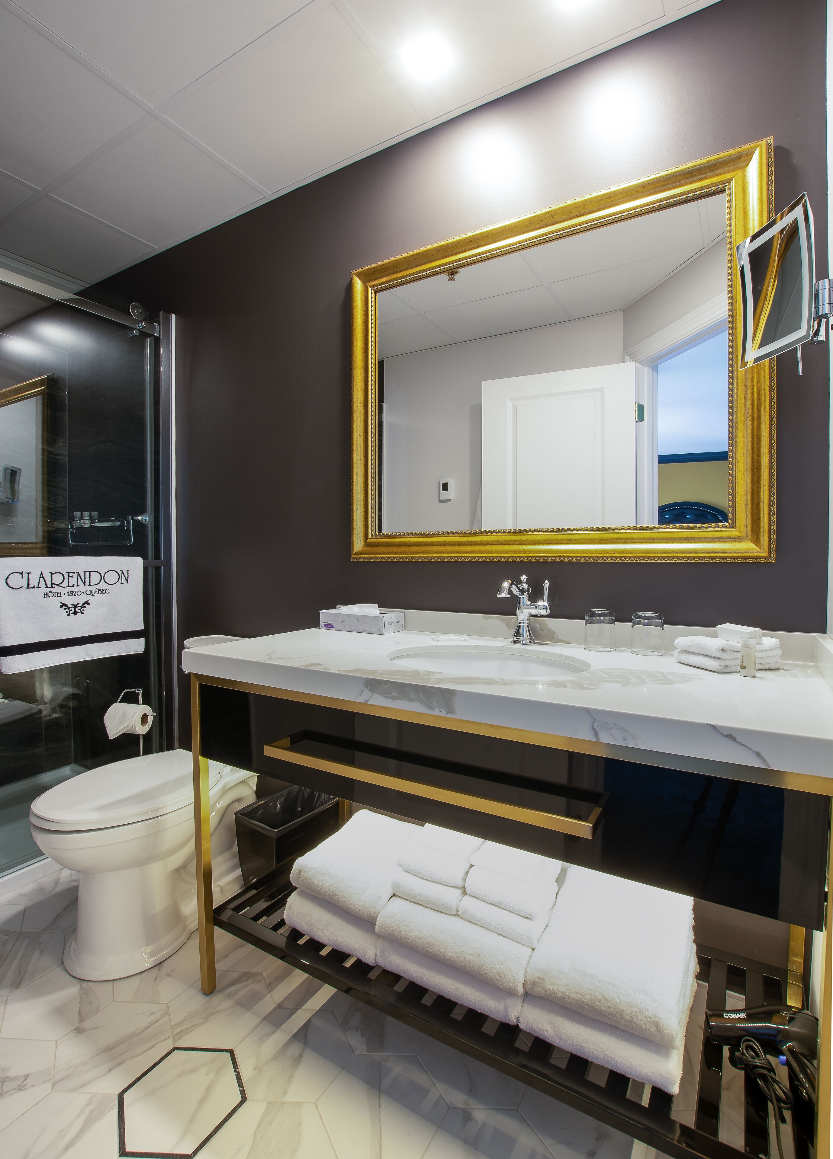 Un baño moderno con un espejo grande, lavamanos blanco y cabina de ducha de vidrio.