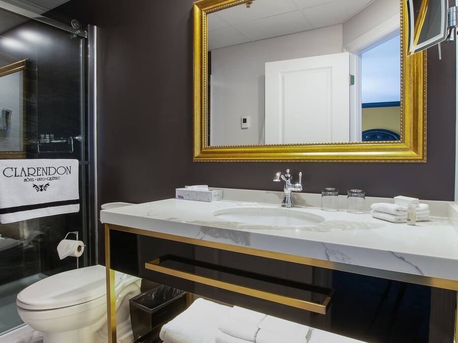 Un baño moderno con un espejo grande, lavamanos blanco y cabina de ducha de vidrio.