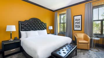 A hotel room with a large bed, a chair, a small table, and a nightstand.