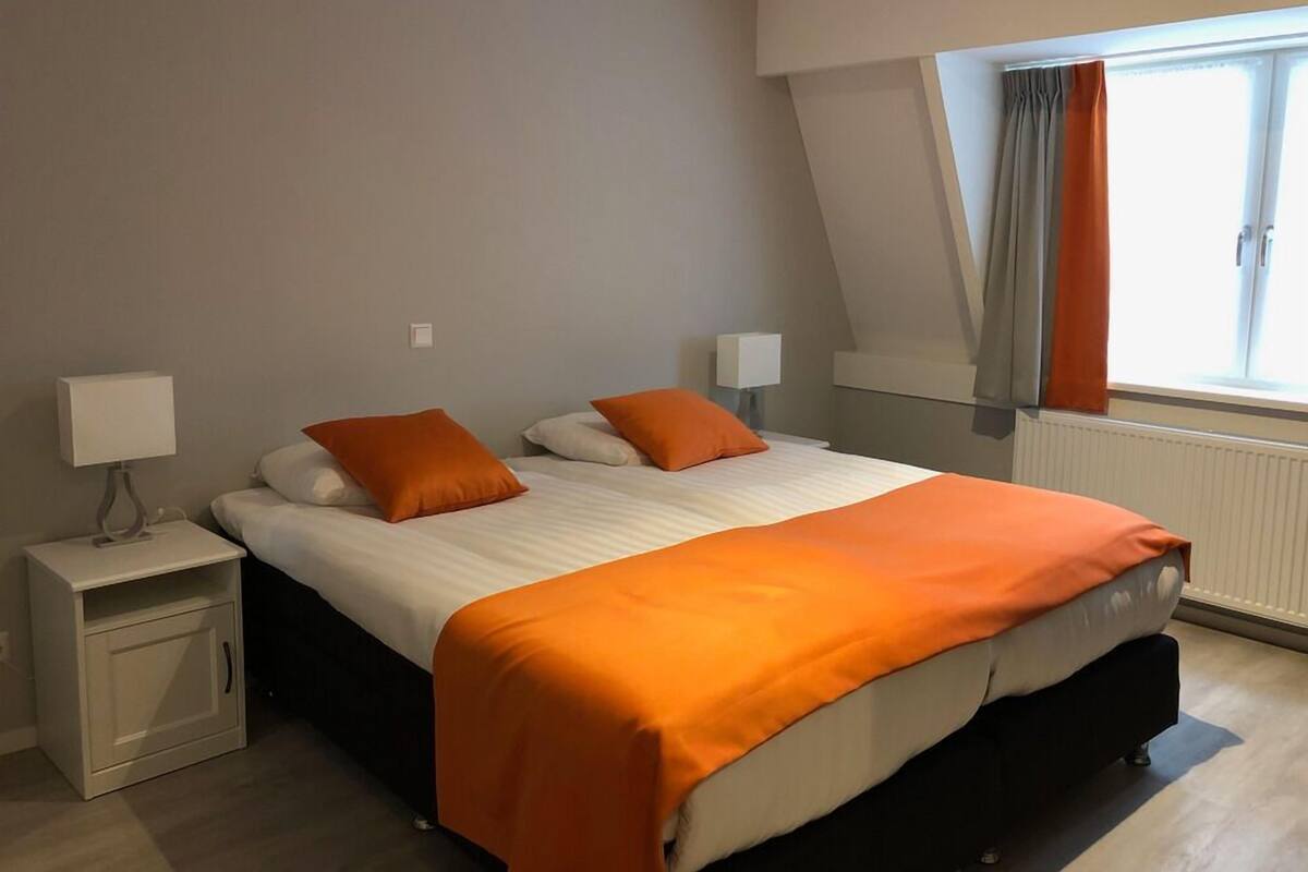 A bedroom with a bed, nightstands, and a window with curtains.