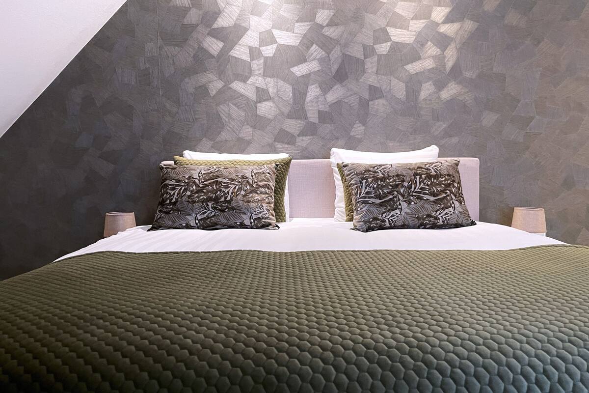 A bed with a geometric patterned wall behind it.