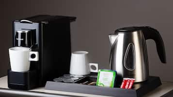 A coffee maker, a kettle, and a tray with tea bags and a mug on a countertop.