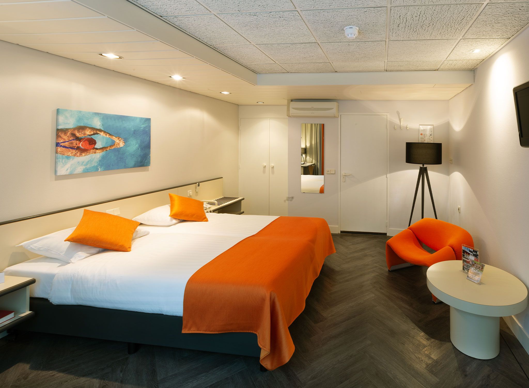 Ein Hotelzimmer mit einem Bett, einem Schreibtisch, einem Stuhl und einem kleinen Tisch.
