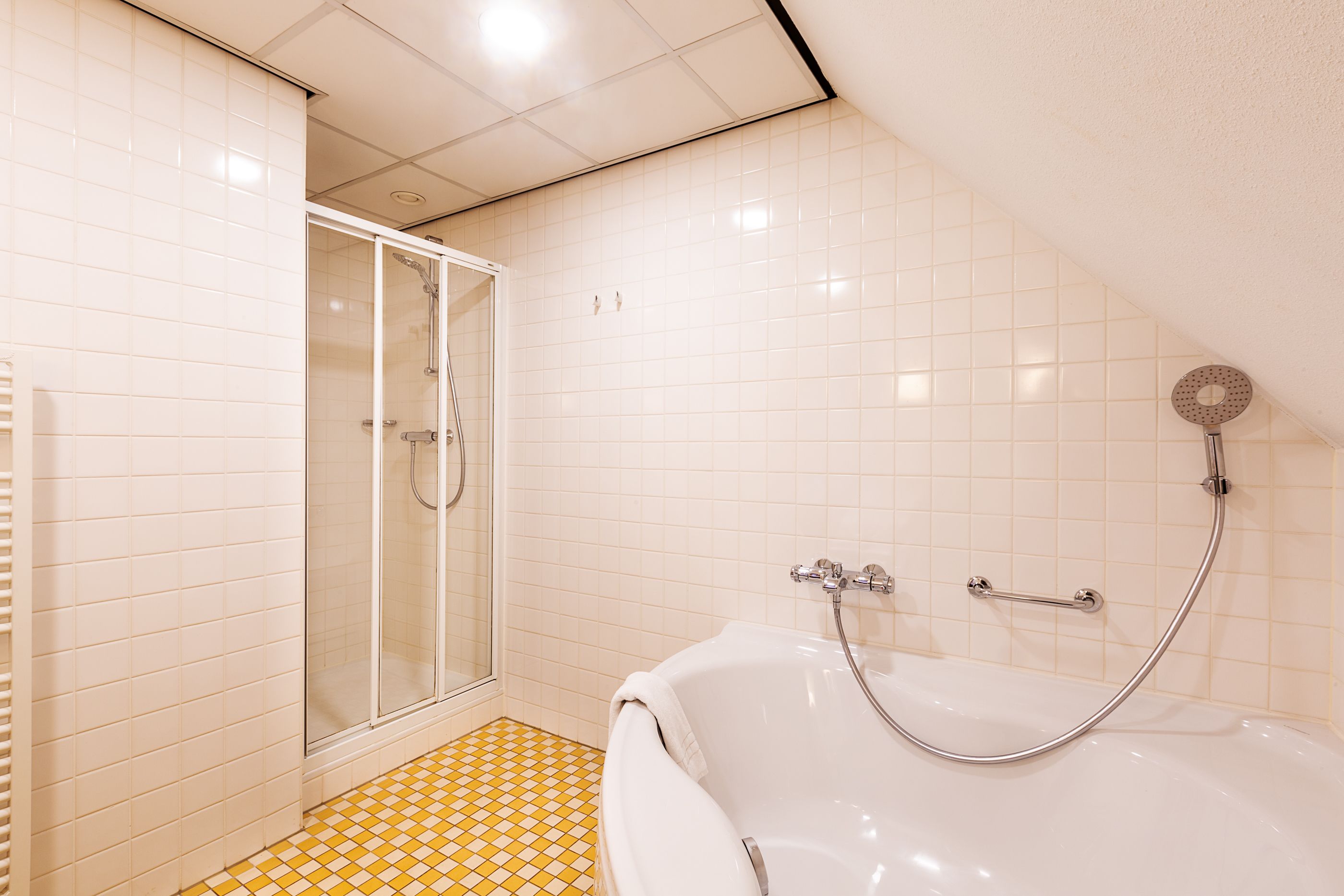 Un baño con ducha, bañera y suelo de baldosas.