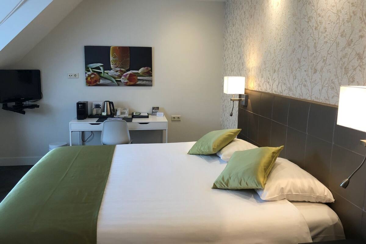 A hotel room with a bed, desk, and TV.