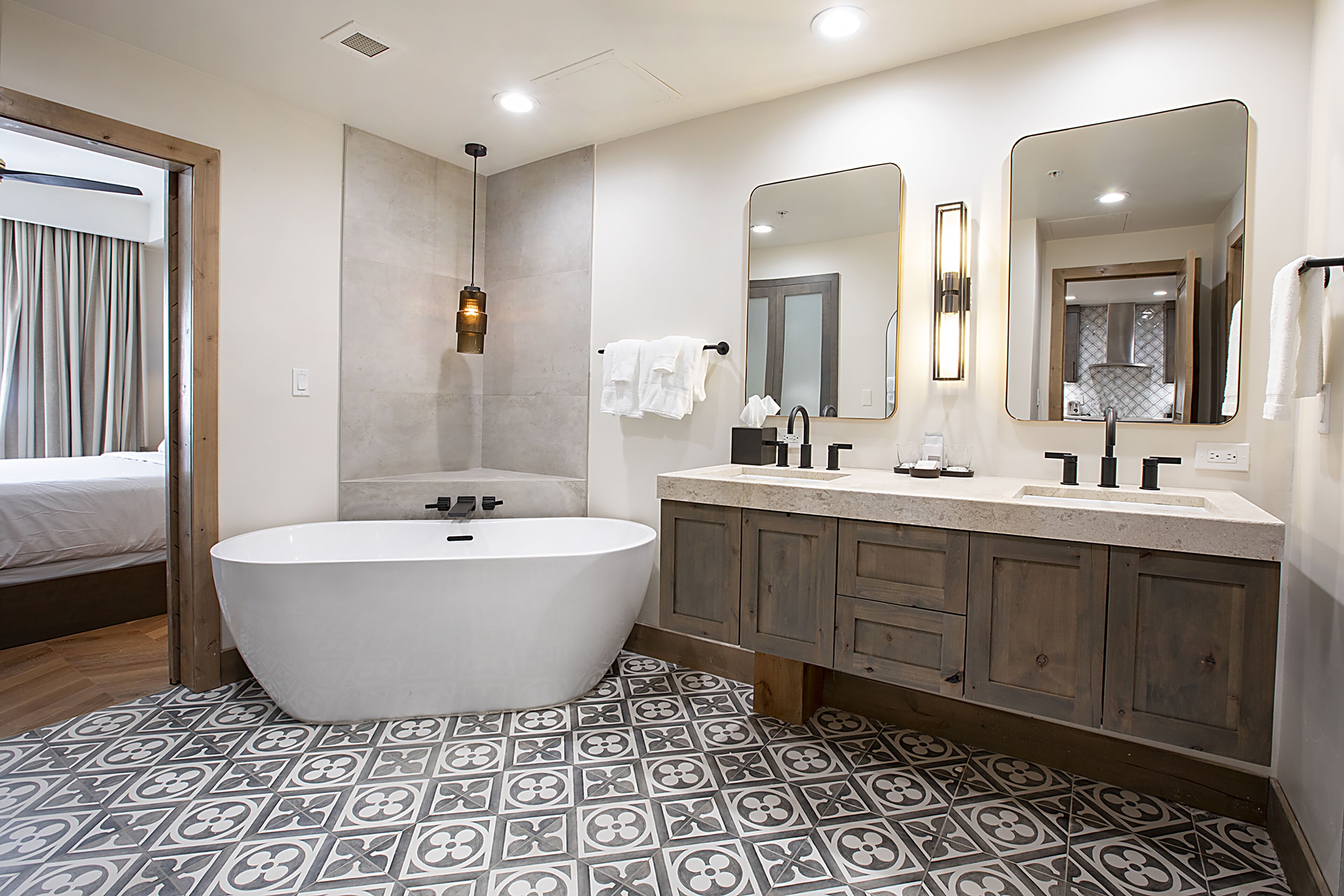 A modern bathroom with a freestanding bathtub, a vanity with a mirror, and patterned floor tiles.