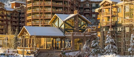 A multi-story hotel with balconies, a covered entrance, and snow-covered surroundings.