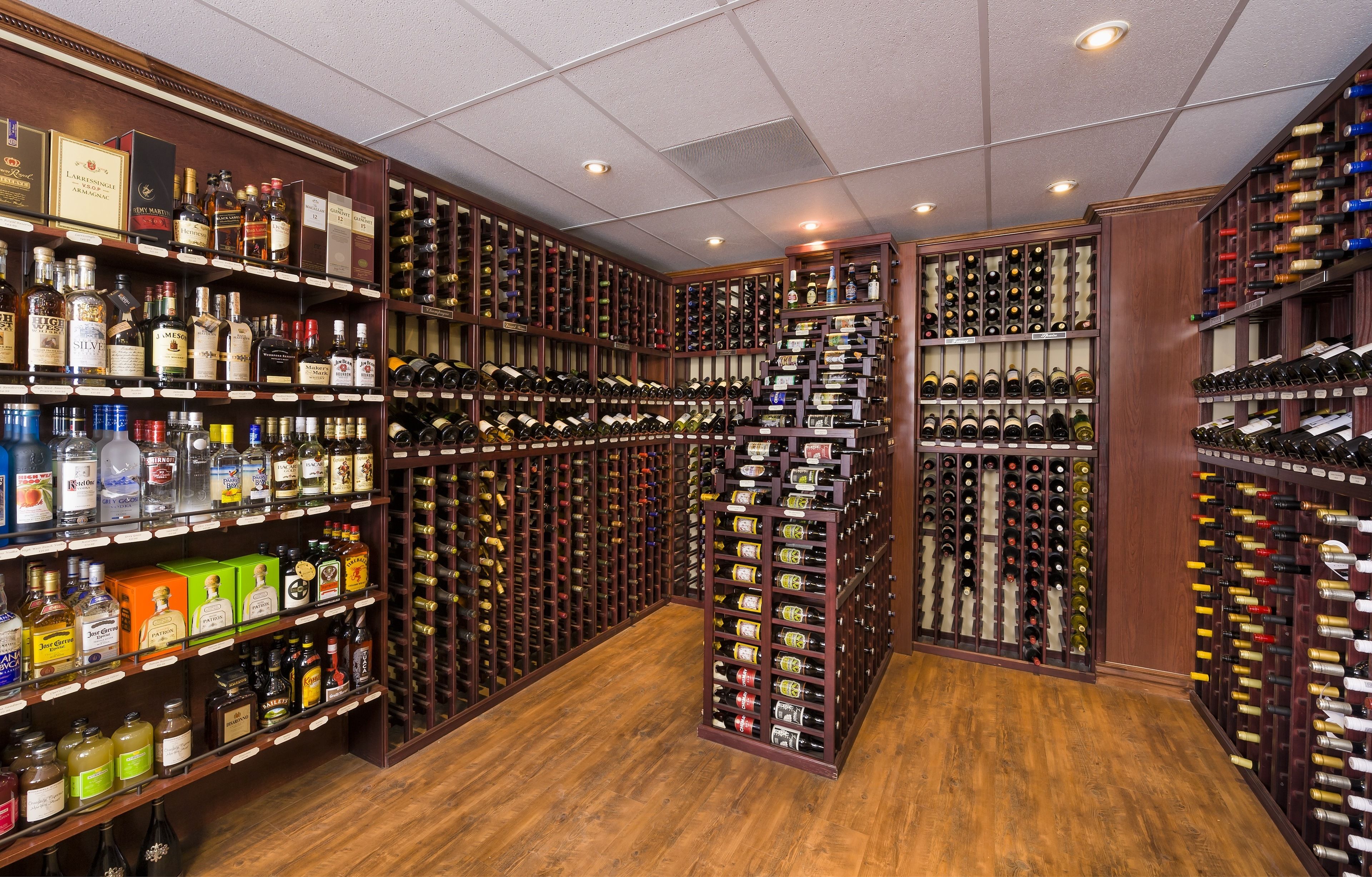 Una bodega con múltiples estantes de madera llenos de botellas de vino y licores.