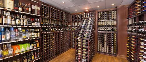 Una bodega con múltiples estantes de madera llenos de botellas de vino y licores.