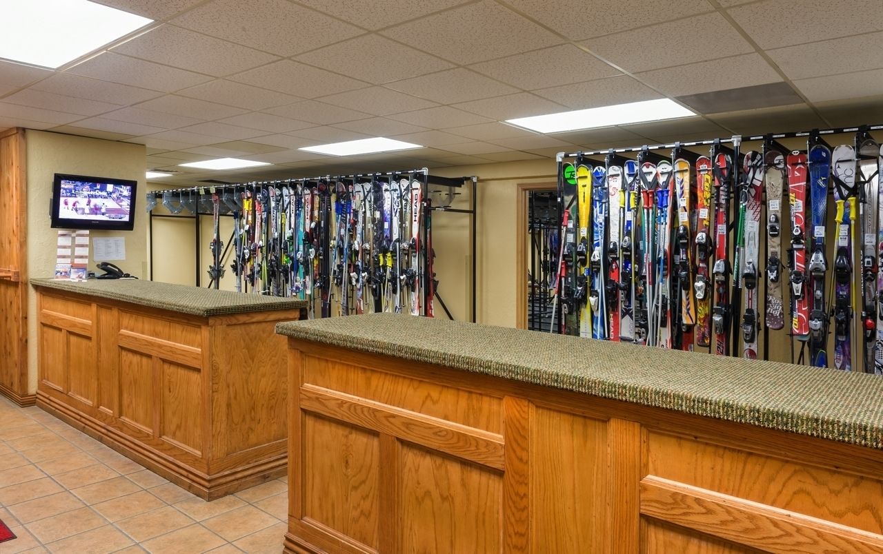 A ski rental counter with wooden paneling and a television screen displaying a sports event.