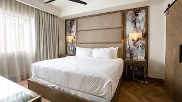 Ein modernes Hotelzimmer mit einem großen Bett, einem Schreibtisch, einem Deckenventilator und einer Wandleuchte.