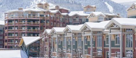 A multi-story hotel with balconies and a view of snow-covered mountains.