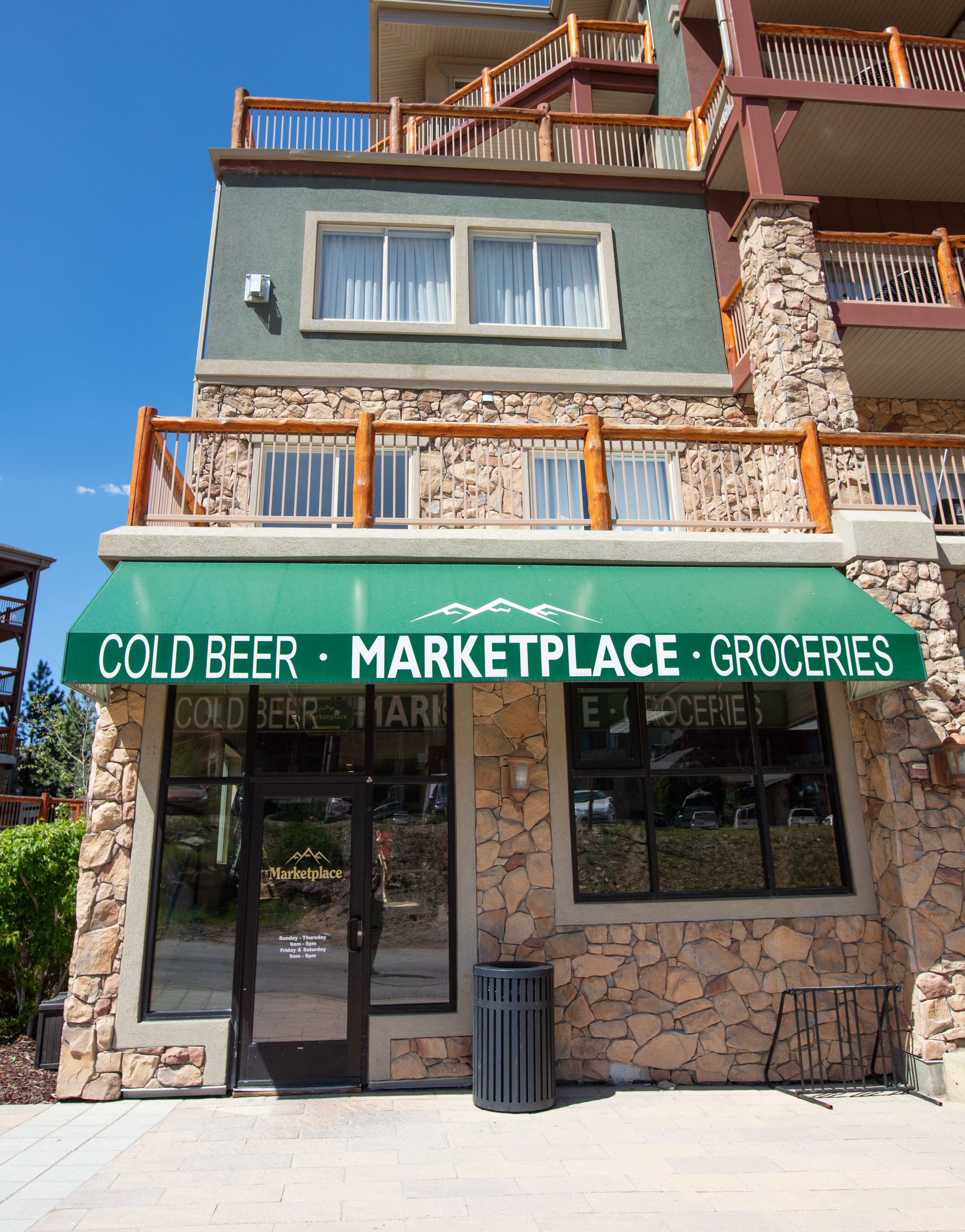 Un edificio de varios pisos con una fachada que muestra el rótulo "COLD BEER MARKETPLACE GROCERIES".