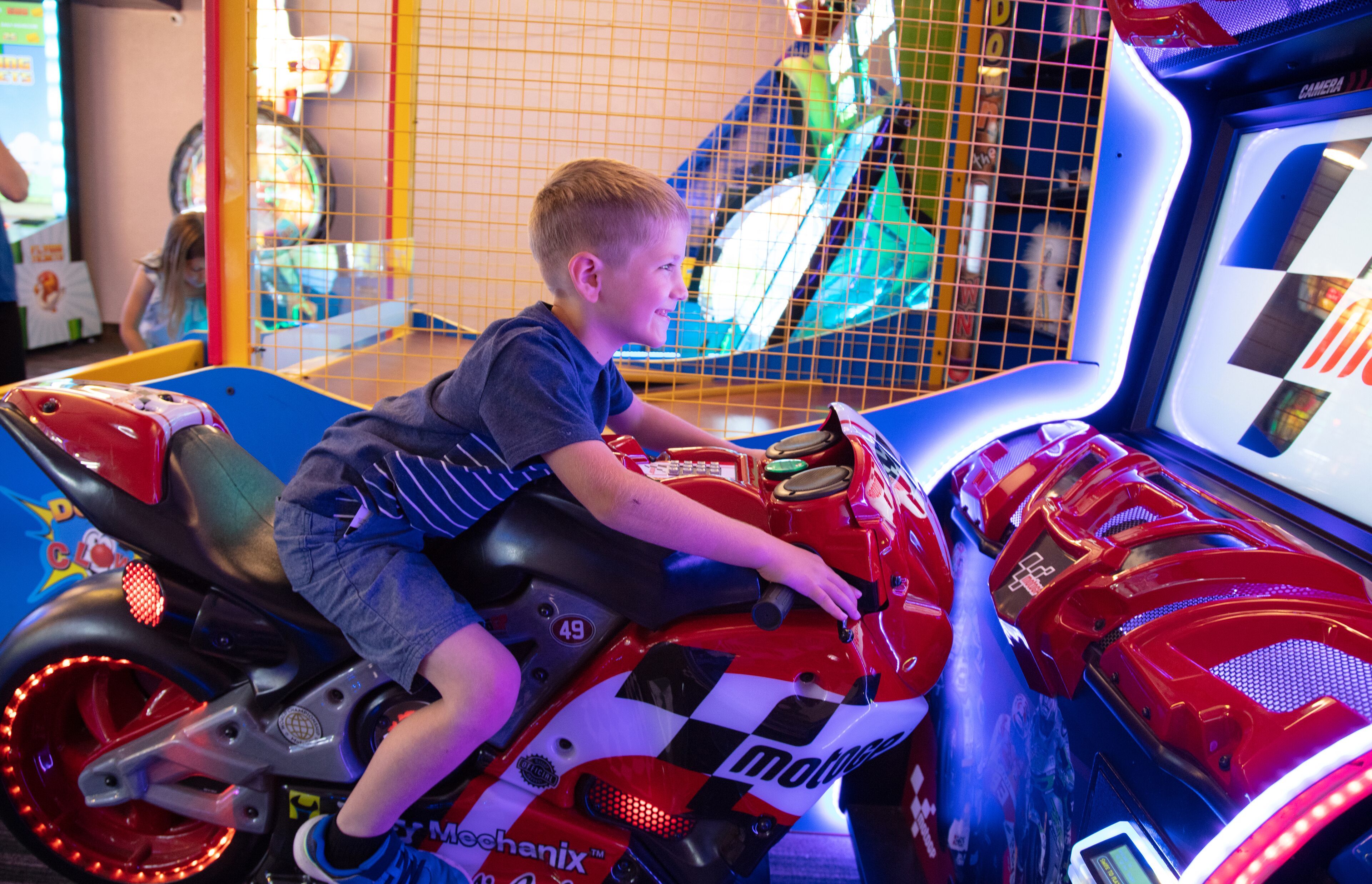 Un bambino guida una motocicletta rossa e bianca con decorazioni a scacchi e il numero 49.