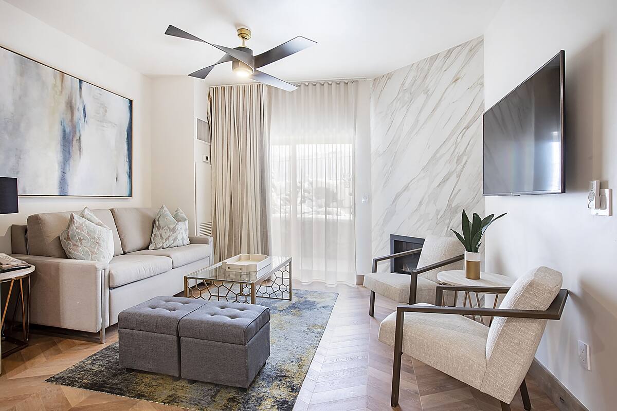 Una sala de estar moderna con sofá, otomanas, mesa de centro y sillón.
