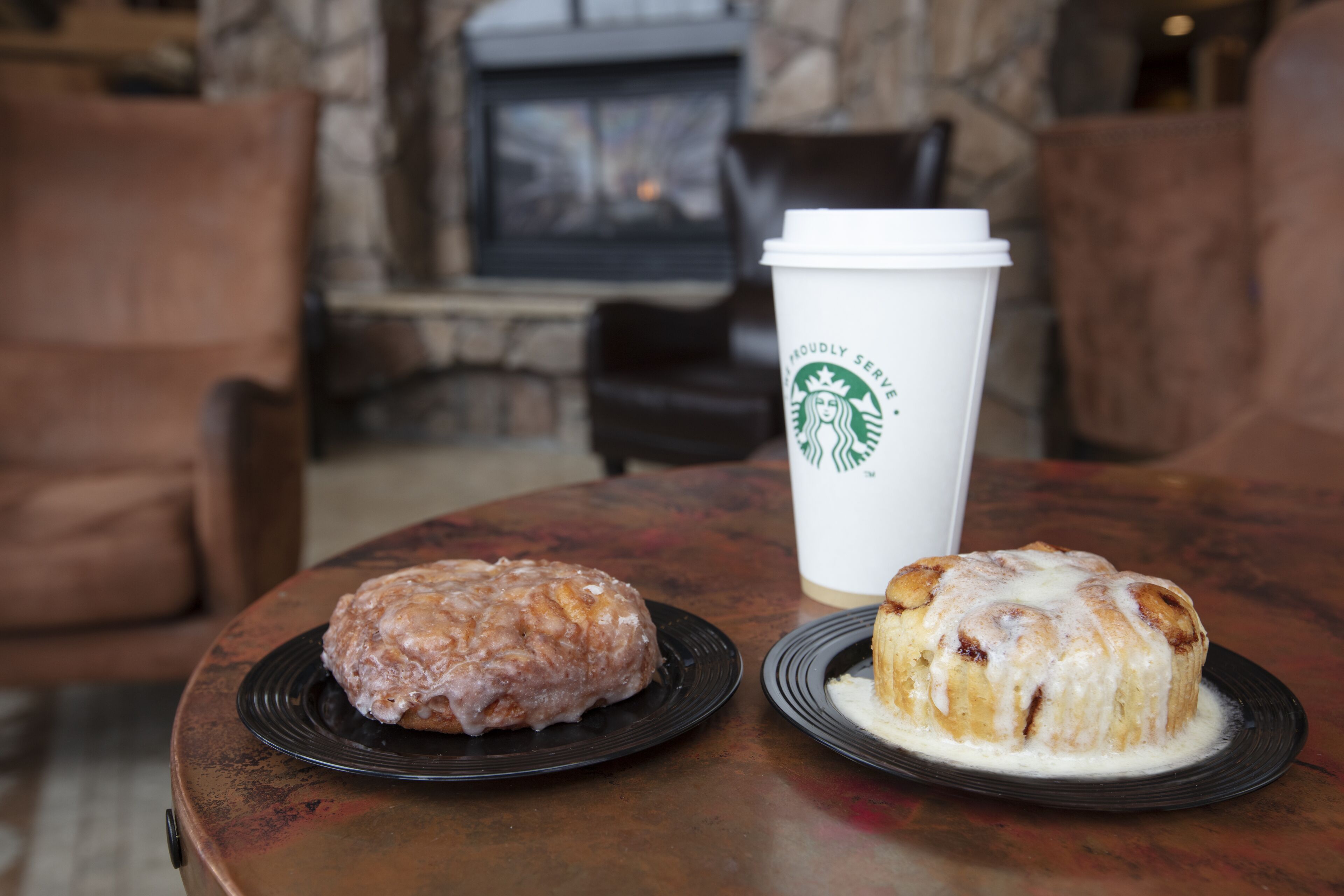 Een tafel met twee gebakjes en een Starbucks-beker.
