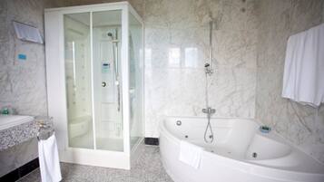 A modern bathroom with a glass-enclosed shower, a freestanding bathtub, and a marble-tiled wall.