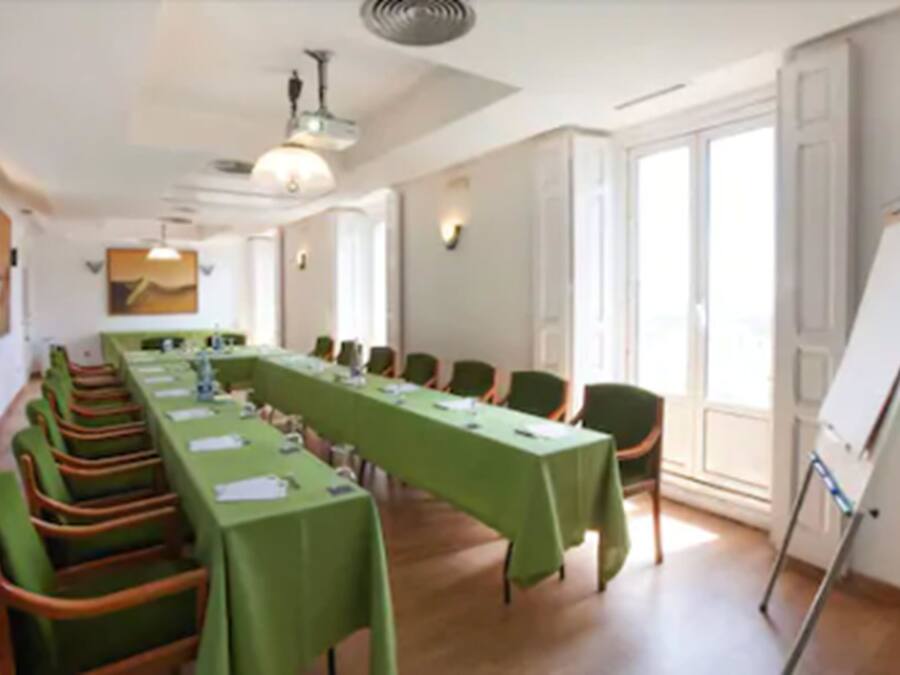 A conference room with a long table, chairs, a whiteboard, and large windows.