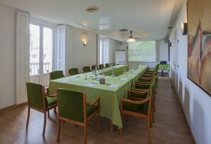 Un salón de conferencias con una larga mesa, sillas verdes y una pantalla de proyector mostrando "hotel Florido".