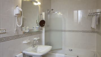 Een badkamer met een wastafel, spiegel, haardroger en douche.