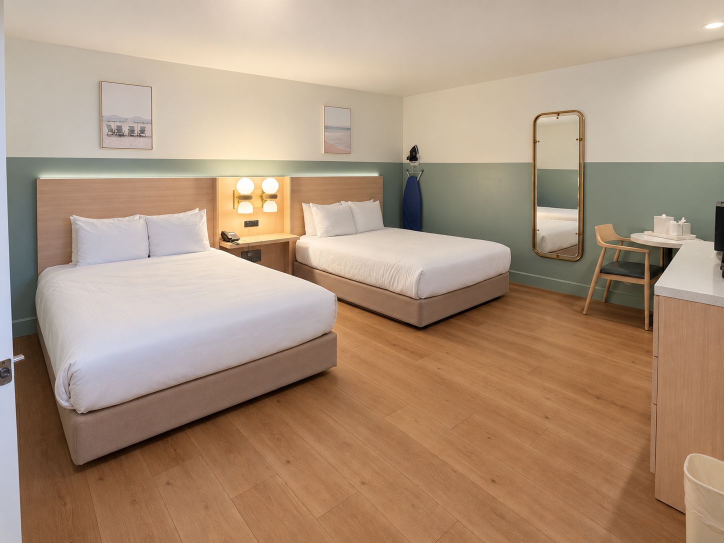 Habitación de hotel con dos camas, un escritorio, una silla y un espejo.