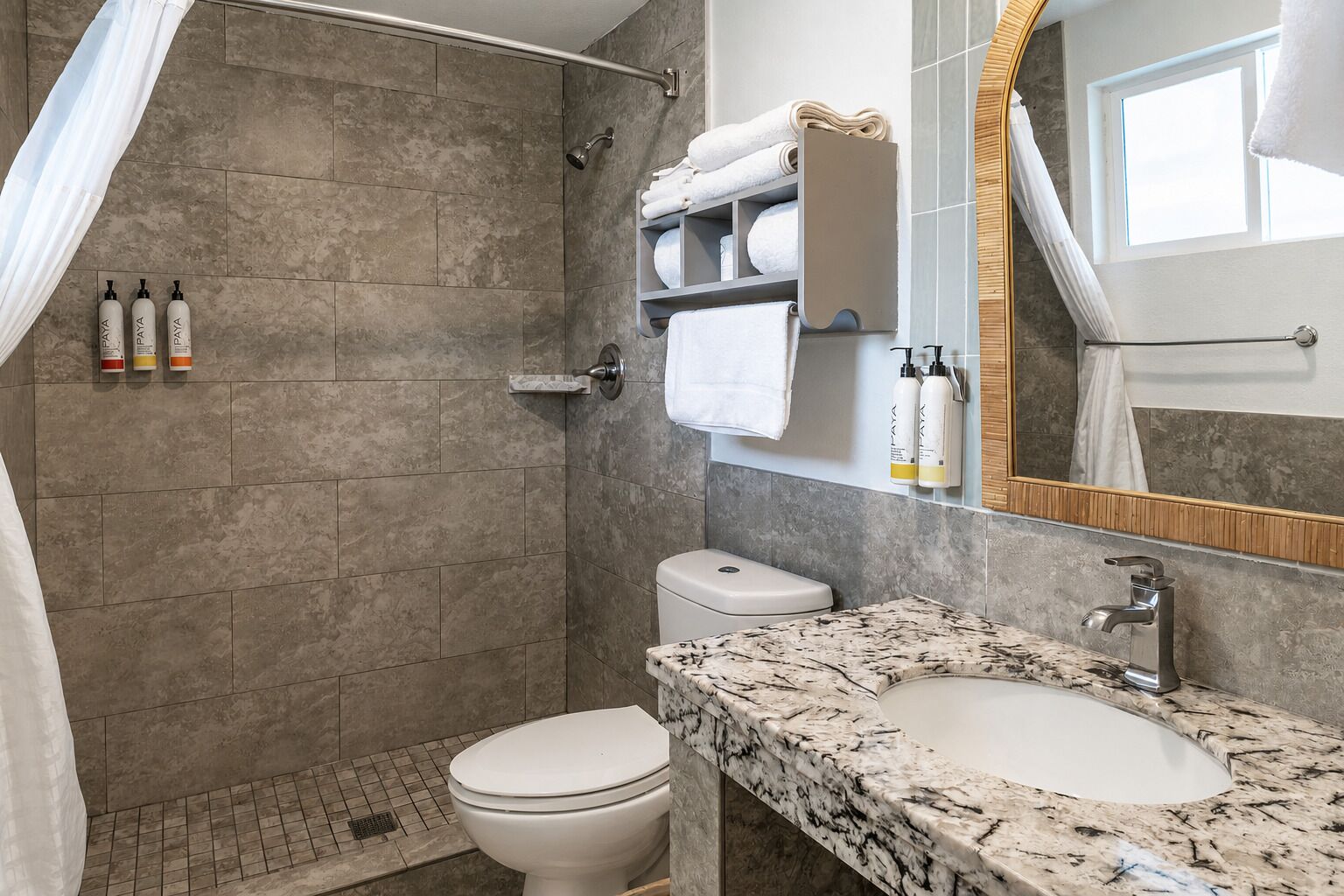 A modern bathroom with a shower, toilet, and marble sink.