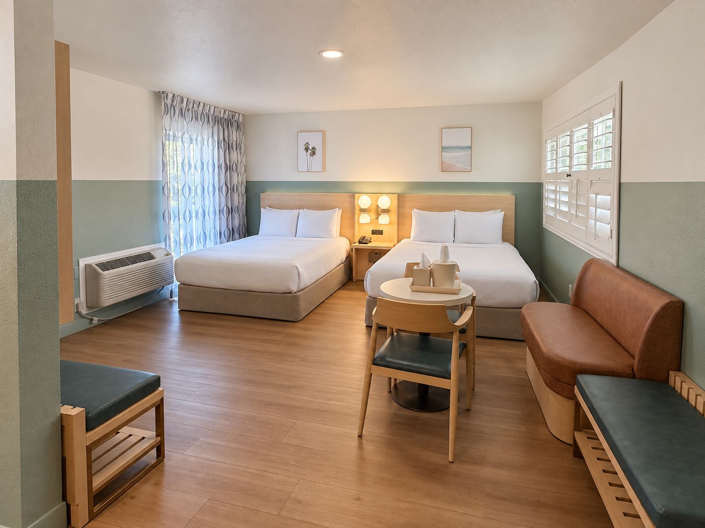 A hotel room with two beds, a small table with a chair, a sofa, and a window with curtains.