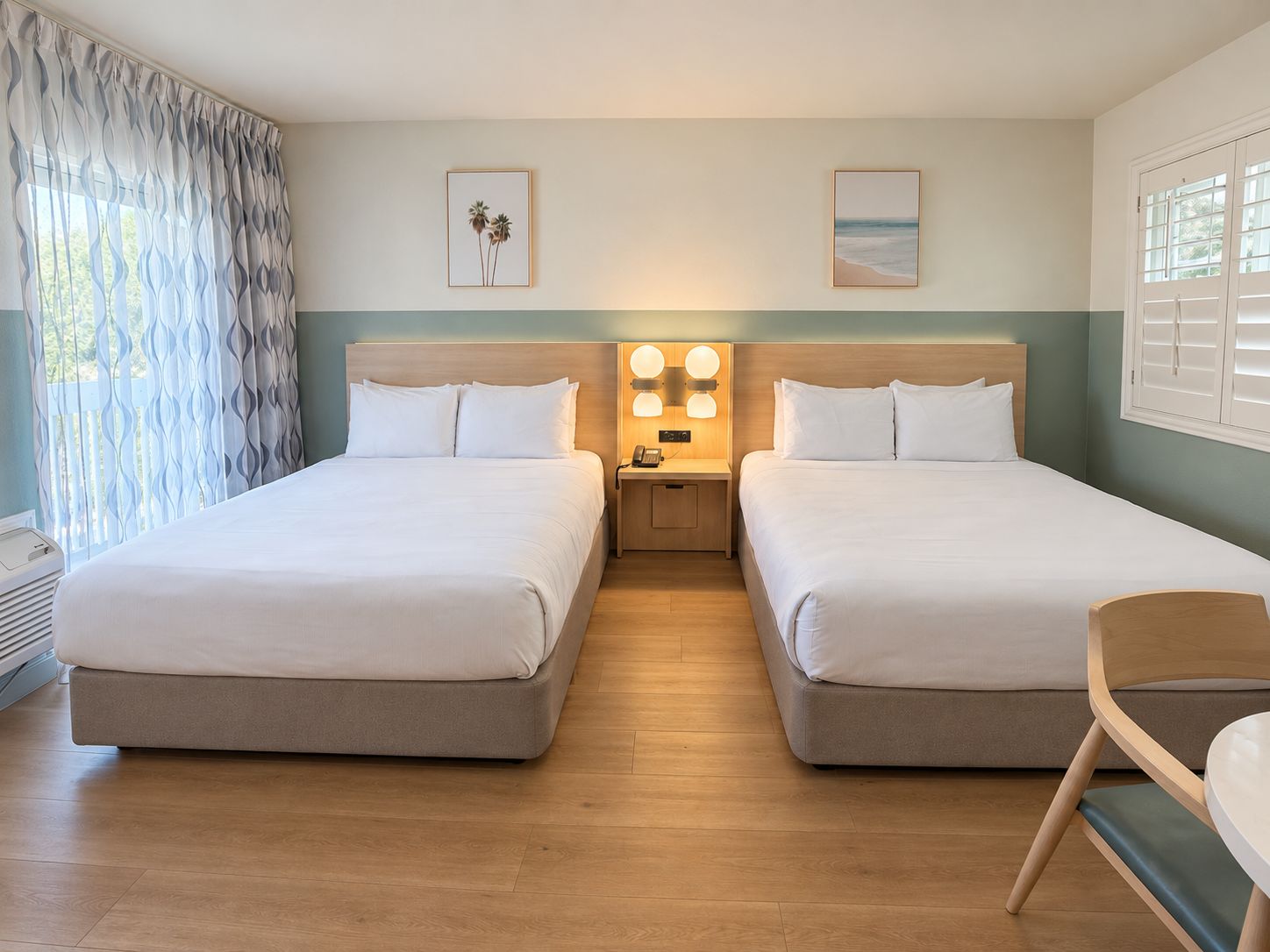 Une chambre d’hôtel avec deux lits, une table de chevet avec une lampe et une chaise.