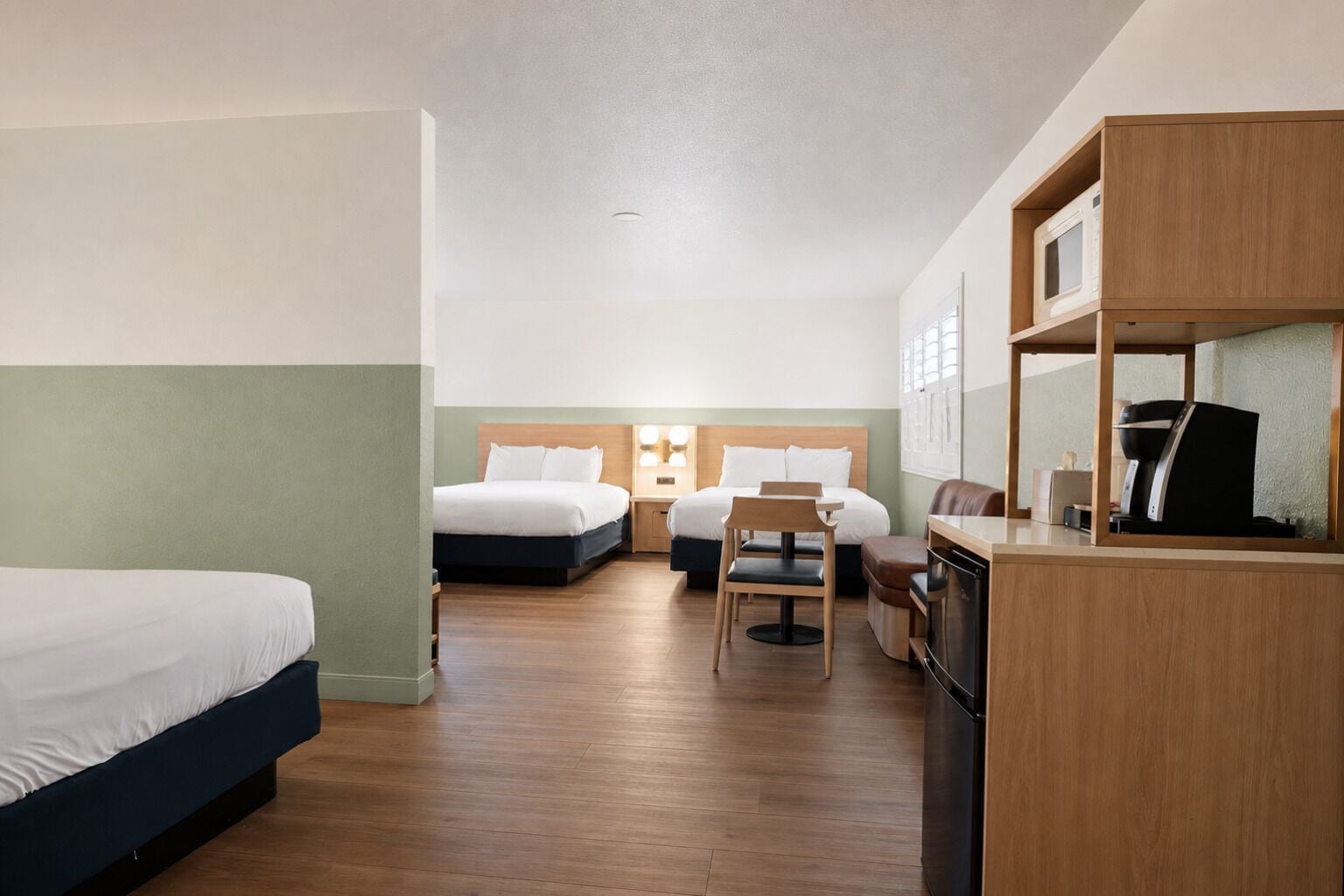 A hotel room with two beds, a desk, a chair, and a television.