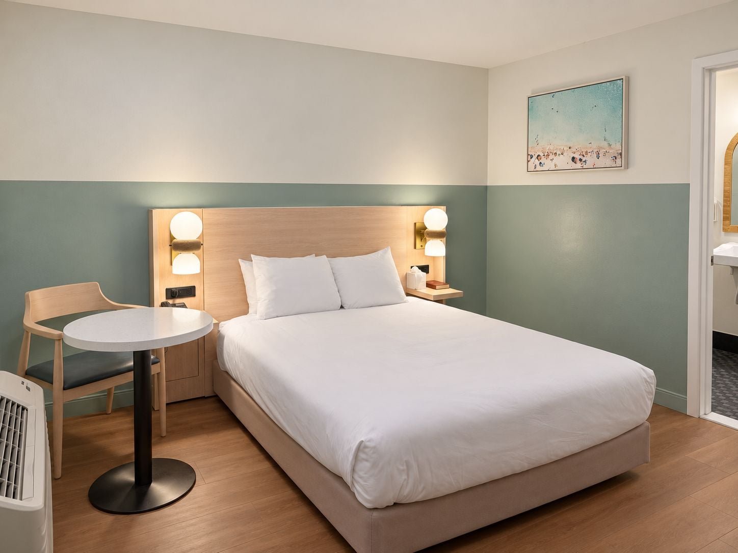 Une chambre d’hôtel avec un lit, des tables de chevet, une chaise et une table ronde.