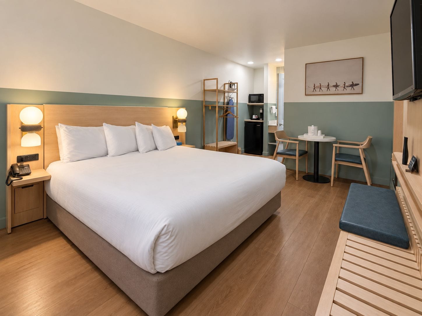 Hotellihuone, jossa on suuri sänky, yöpöydät, työpöytä, tuoli, televisio ja peili.