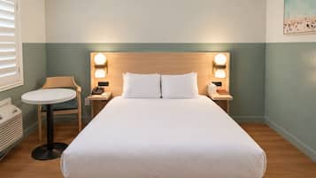 A hotel room with a bed, bedside tables, a chair, and a small table.
