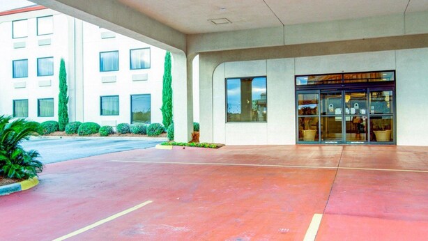 A modern hotel entrance with a covered walkway, a glass door entrance, and a parking area.