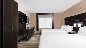 A hotel room with a large bed, a desk with a chair, a TV, and a window.