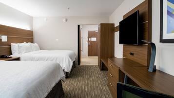 Une chambre d’hôtel avec deux lits, une télévision, un bureau et une porte donnant sur une autre chambre.
