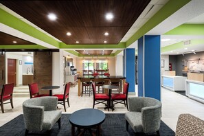 A modern indoor dining area with a wooden ceiling, green and blue walls, and a central dining table surrounded by chairs. - Holiday Inn Express Hillsville by IHG (Hillsville)