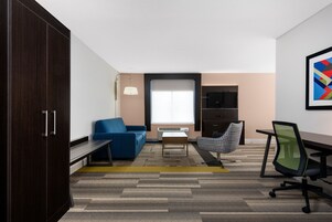 Un espacio de oficina moderno con un armario de madera oscura, un sofá azul, una pequeña mesa y una silla de oficina verde.
