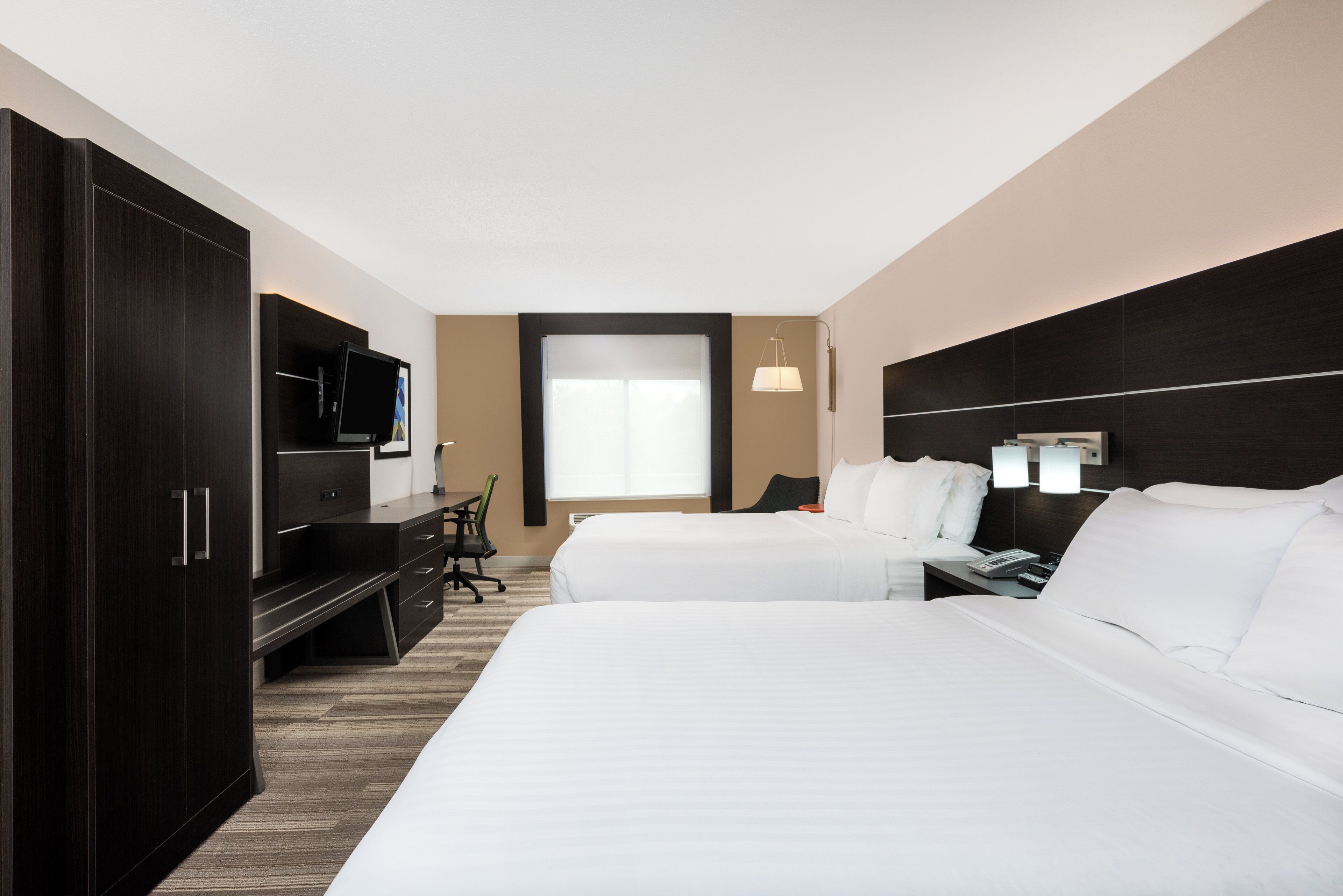 Une chambre d’hôtel avec deux lits, un bureau, une télévision et une fenêtre.