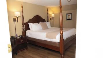 A four-poster bed with a wooden headboard, two bedside tables with lamps, and a framed picture on the wall.
