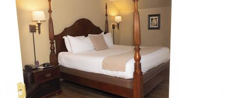 Una cama con dosel con cabecera de madera, dos mesitas de noche con lámparas y un cuadro enmarcado en la pared.