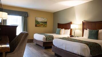 A hotel room with two beds, a desk, and a chair.
