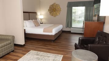 A hotel room with a bed, a desk, a chair, a lamp, and a decorative wall piece.