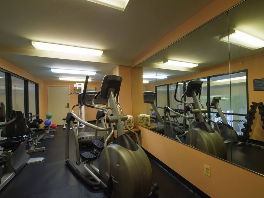 A gym with exercise equipment, a large mirror, and a door.