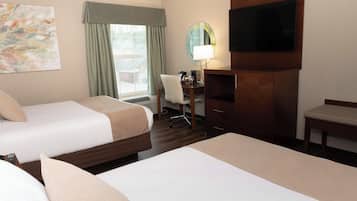 A hotel room with two beds, a desk, a chair, a TV, and a window with curtains.