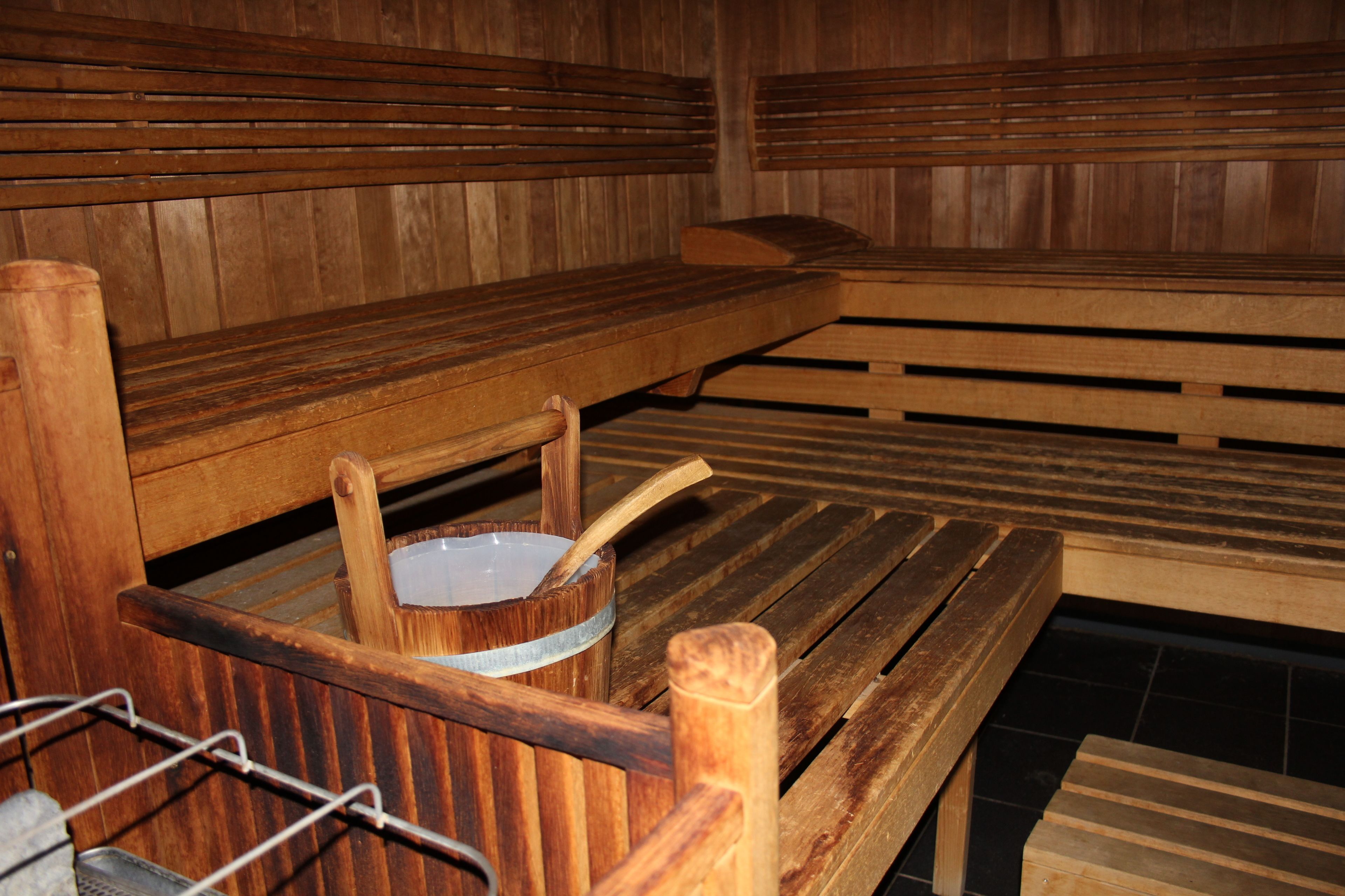 Uma sauna de madeira com bancos e uma pequena mesa com uma tigela e uma colher.