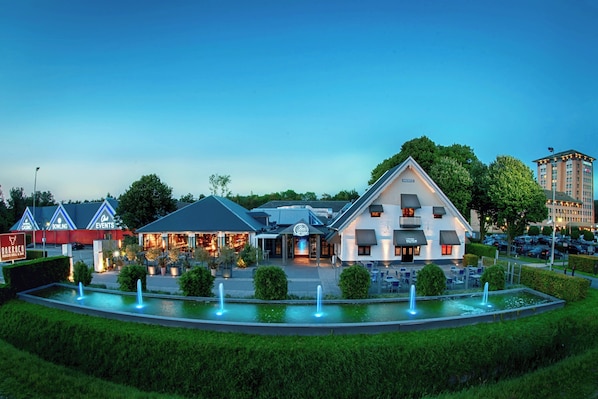Un hôtel composé d’un bâtiment principal et d’une fontaine située à l’avant.
