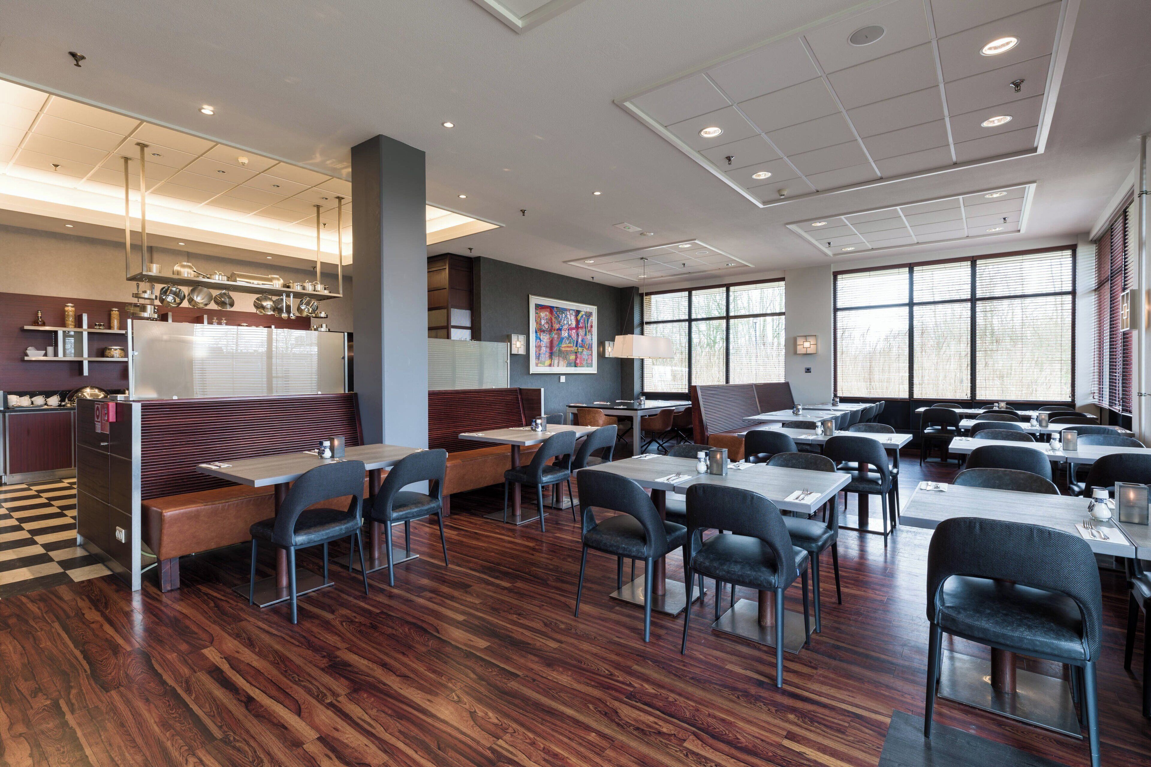 Een modern restaurant met houten vloeren, zitjes en tafels.