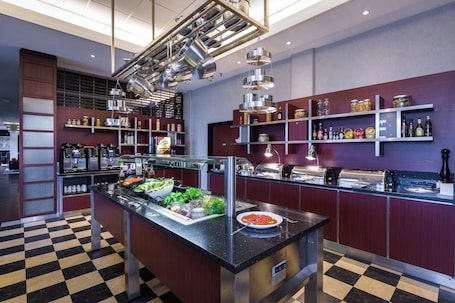A modern kitchen with a checkered floor, stainless steel appliances, and a variety of food items on display.