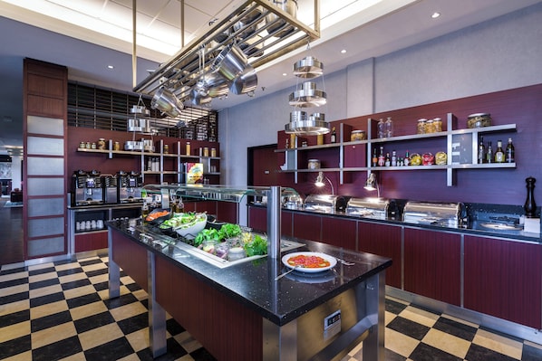 Cocina moderna con piso a cuadros, electrodomésticos de acero inoxidable y diversos alimentos a la vista.