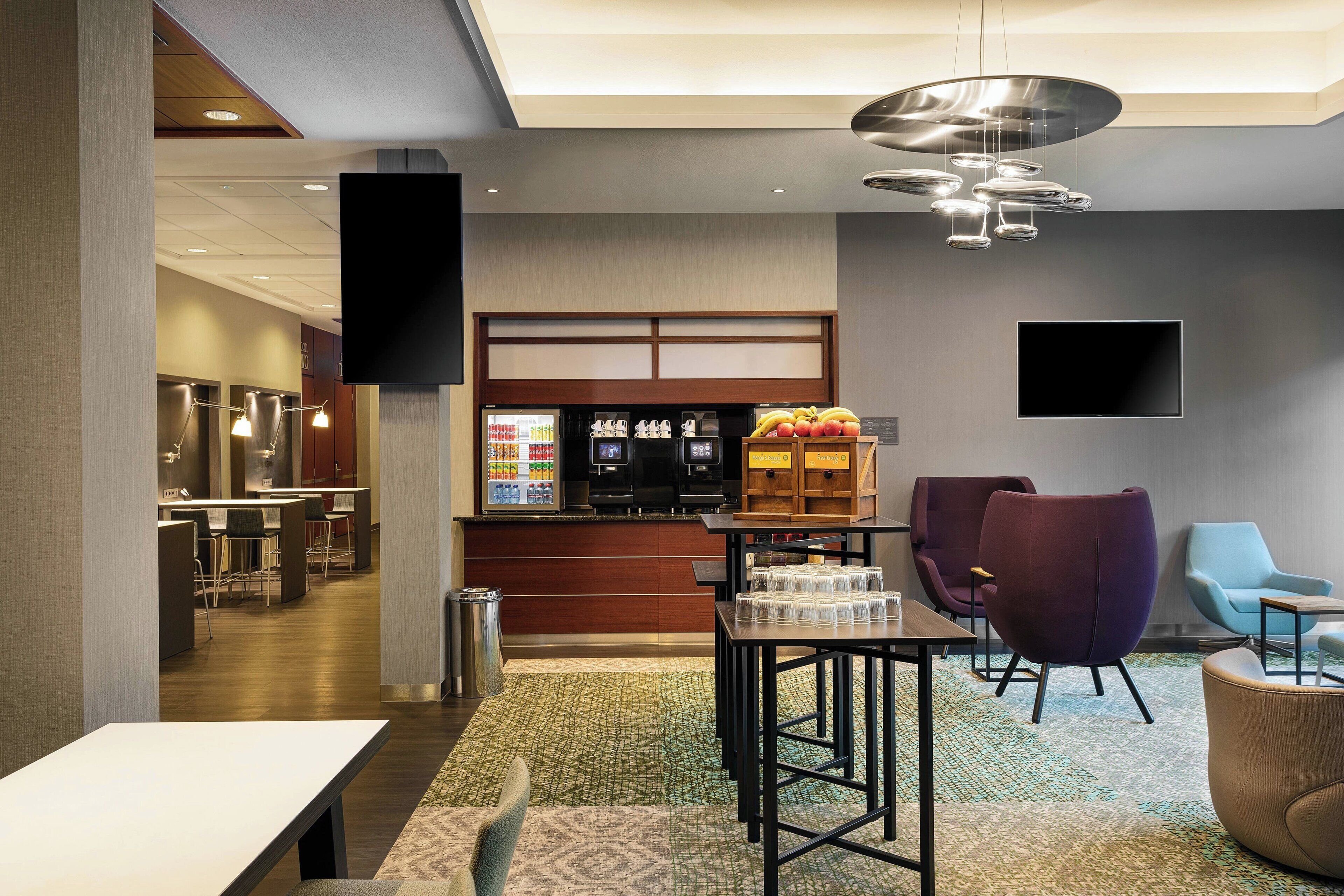 Un moderno vestíbulo de hotel con mostrador de recepción, zona de estar y barra de comidas.